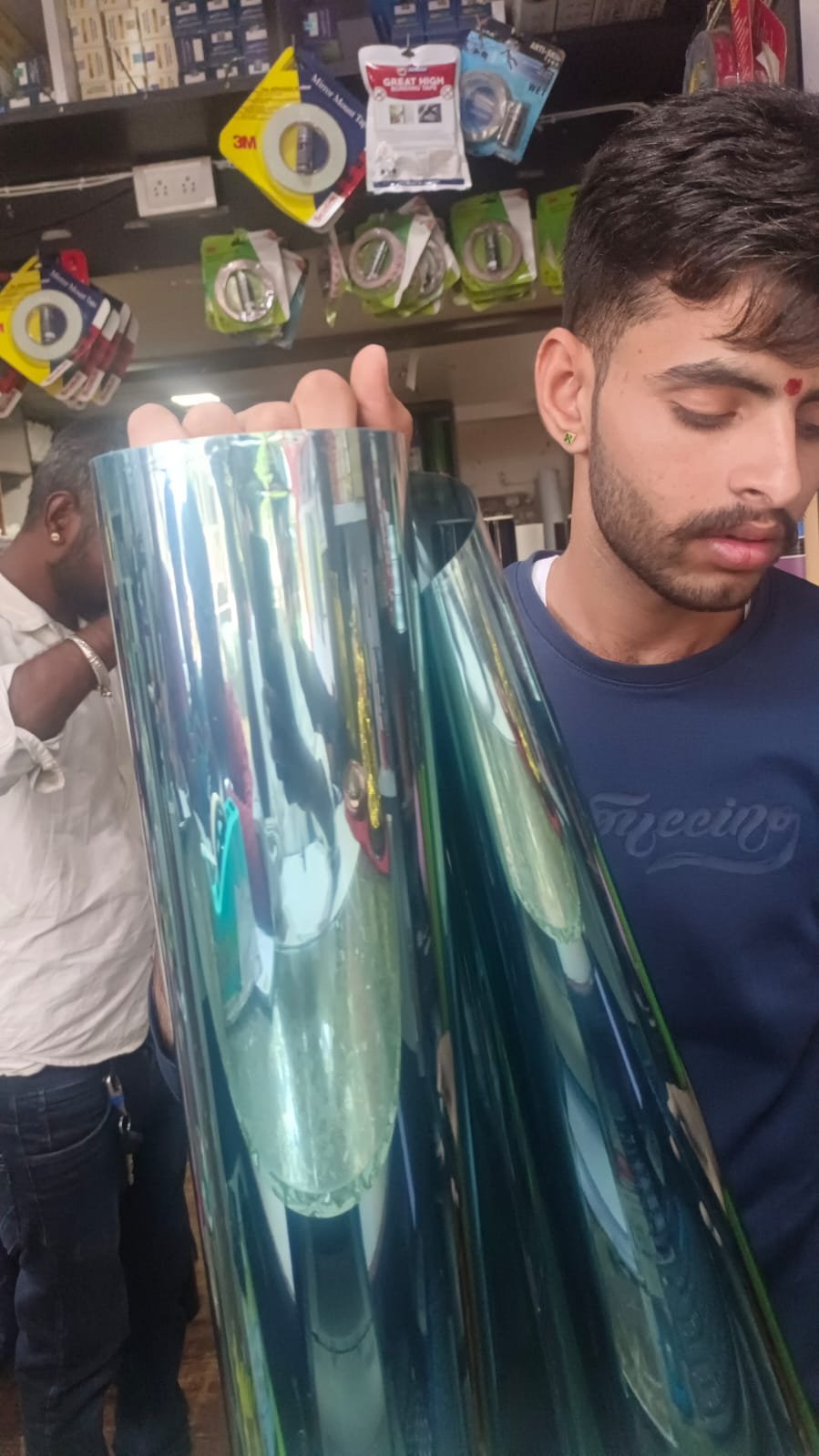 Team holding reflective window film roll at shop